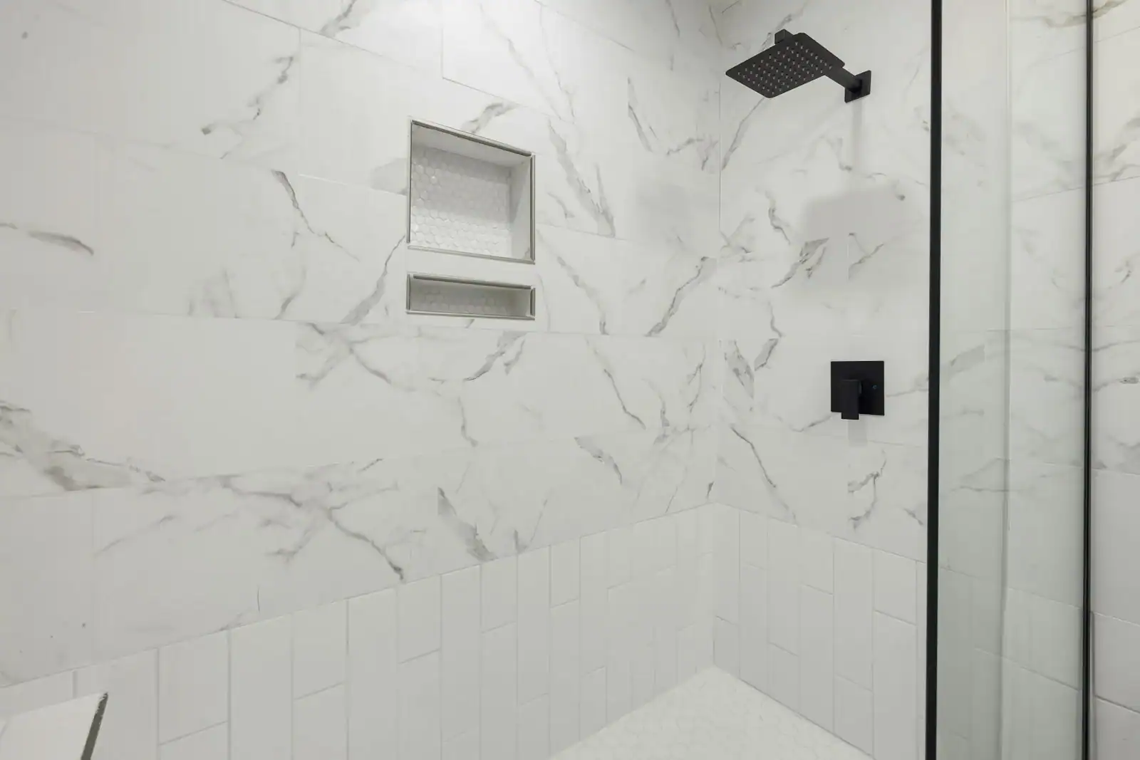Sleek bathroom shower featuring marble tiles and black fixtures, perfect for modern luxury home design.