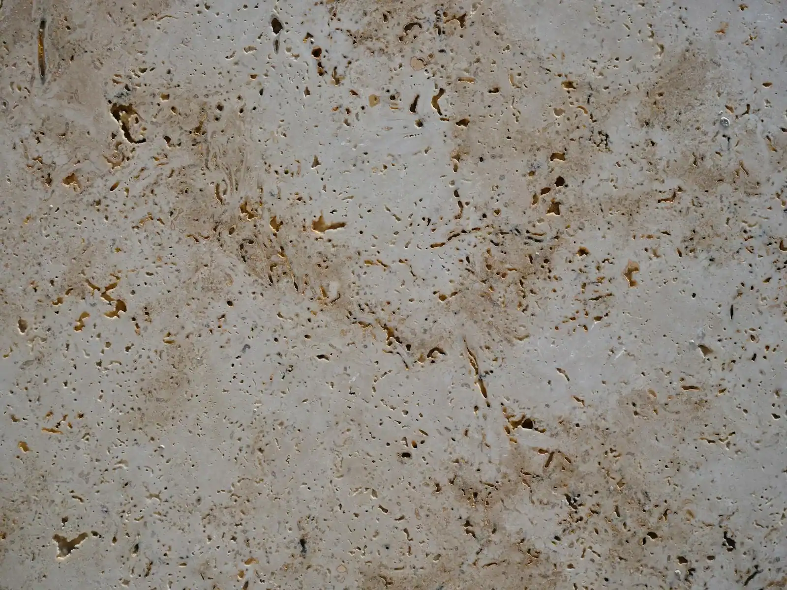 Detailed close-up of a beige stone surface, showcasing its natural texture and earthy tones.