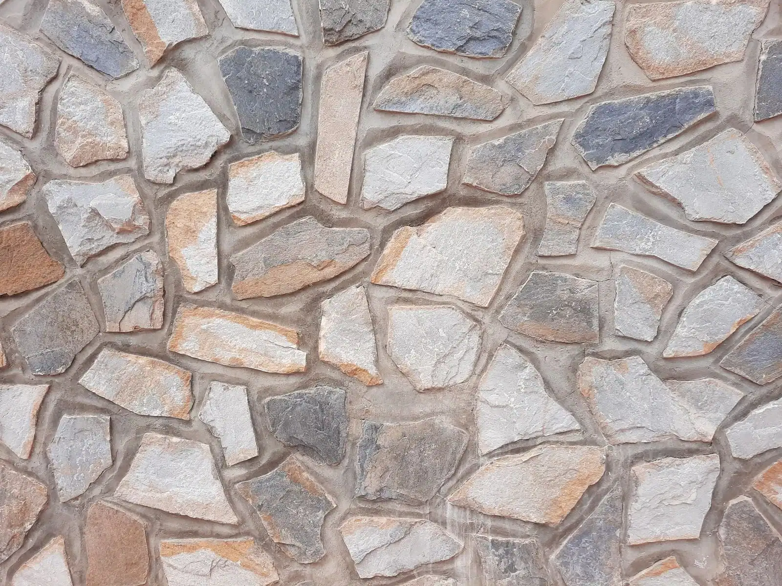 Detailed texture of a rustic stone wall with irregular shapes and earthy tones.