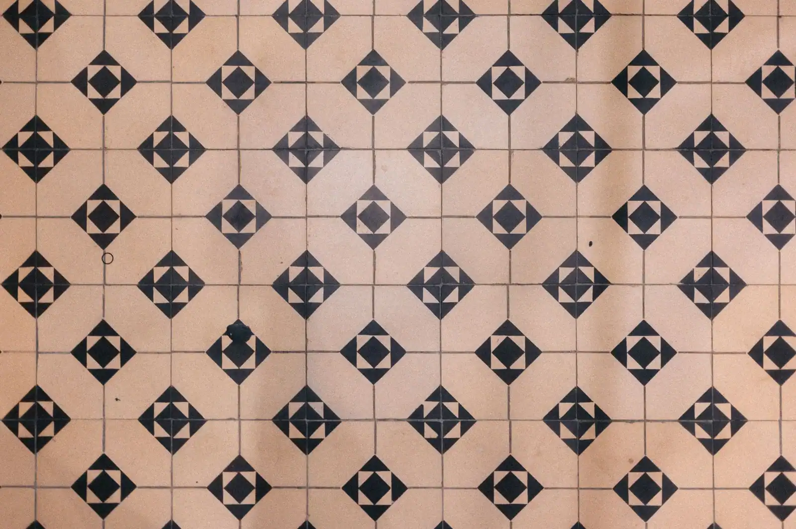 Vintage geometric floor tile pattern with black diamond shapes on beige background.