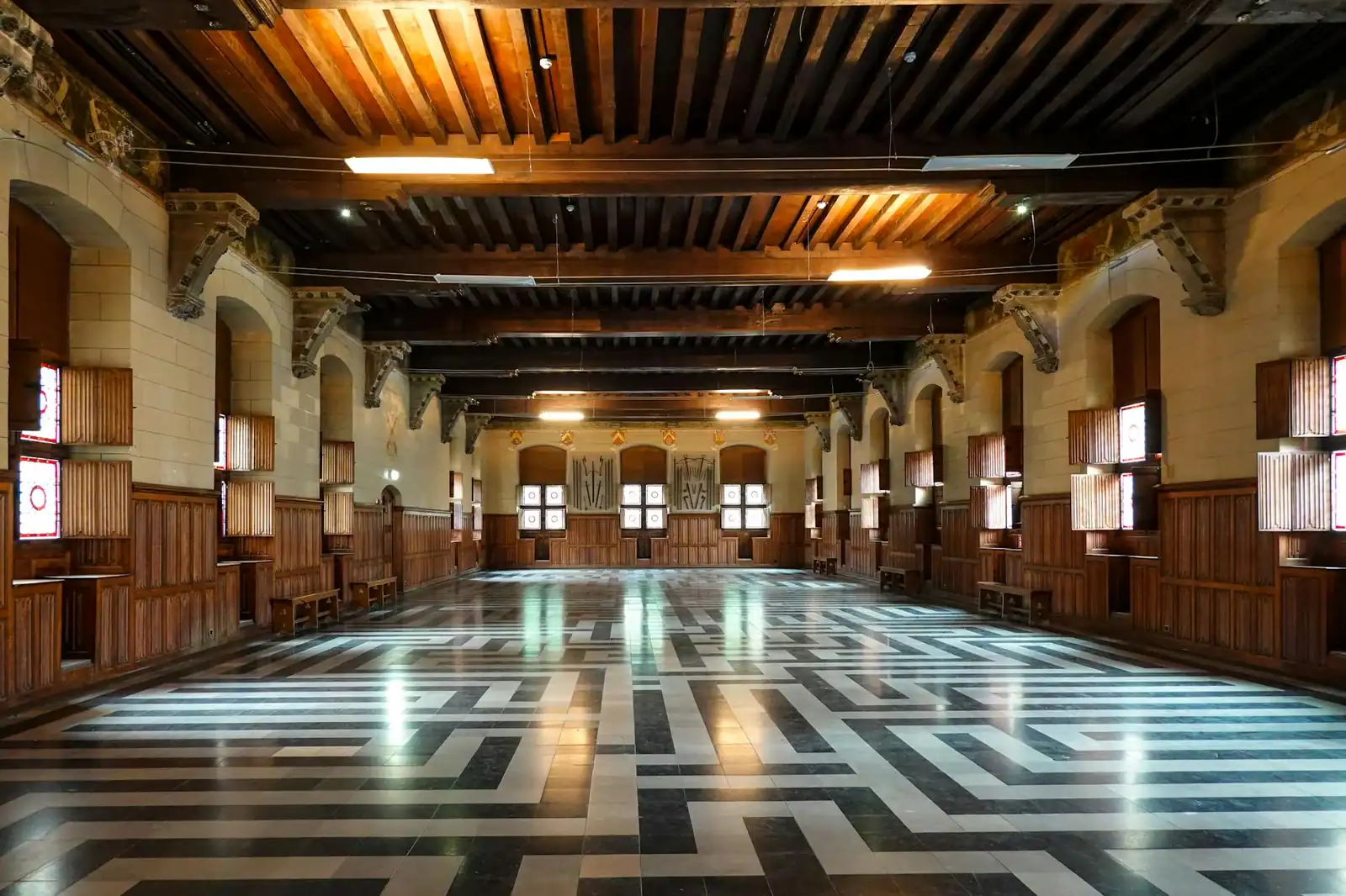 Spacious historic castle hall showcasing intricate woodwork and geometric flooring design.
