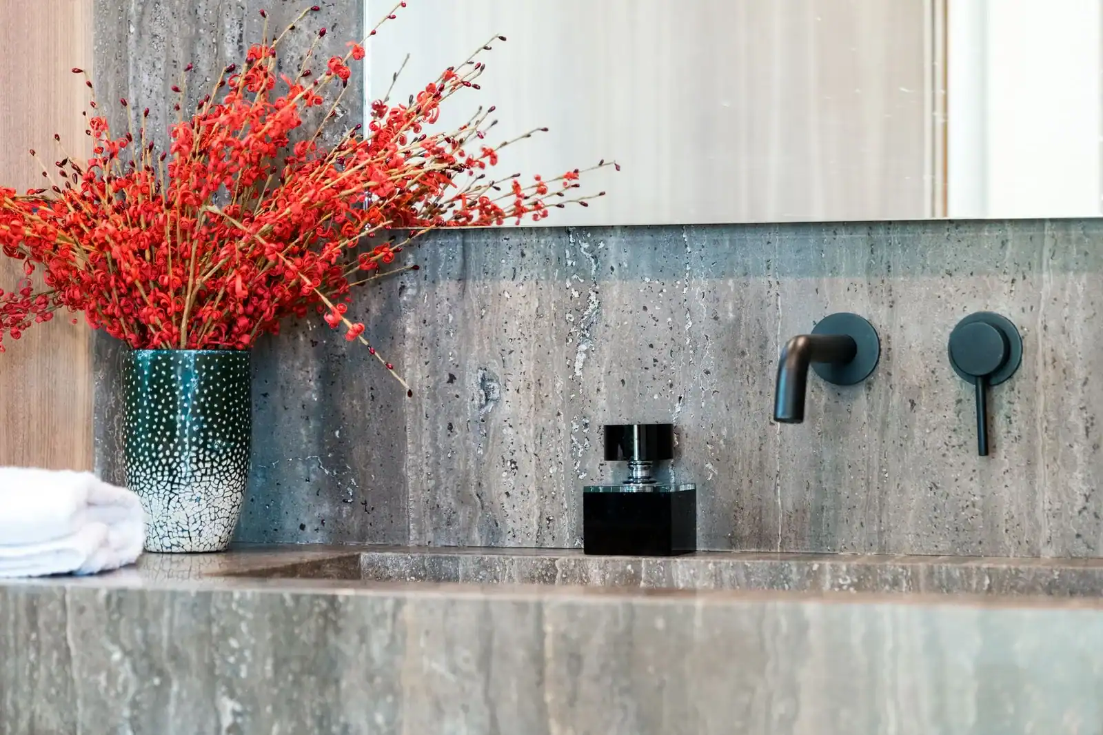 Stylish bathroom with modern fixtures and vibrant red floral arrangement.