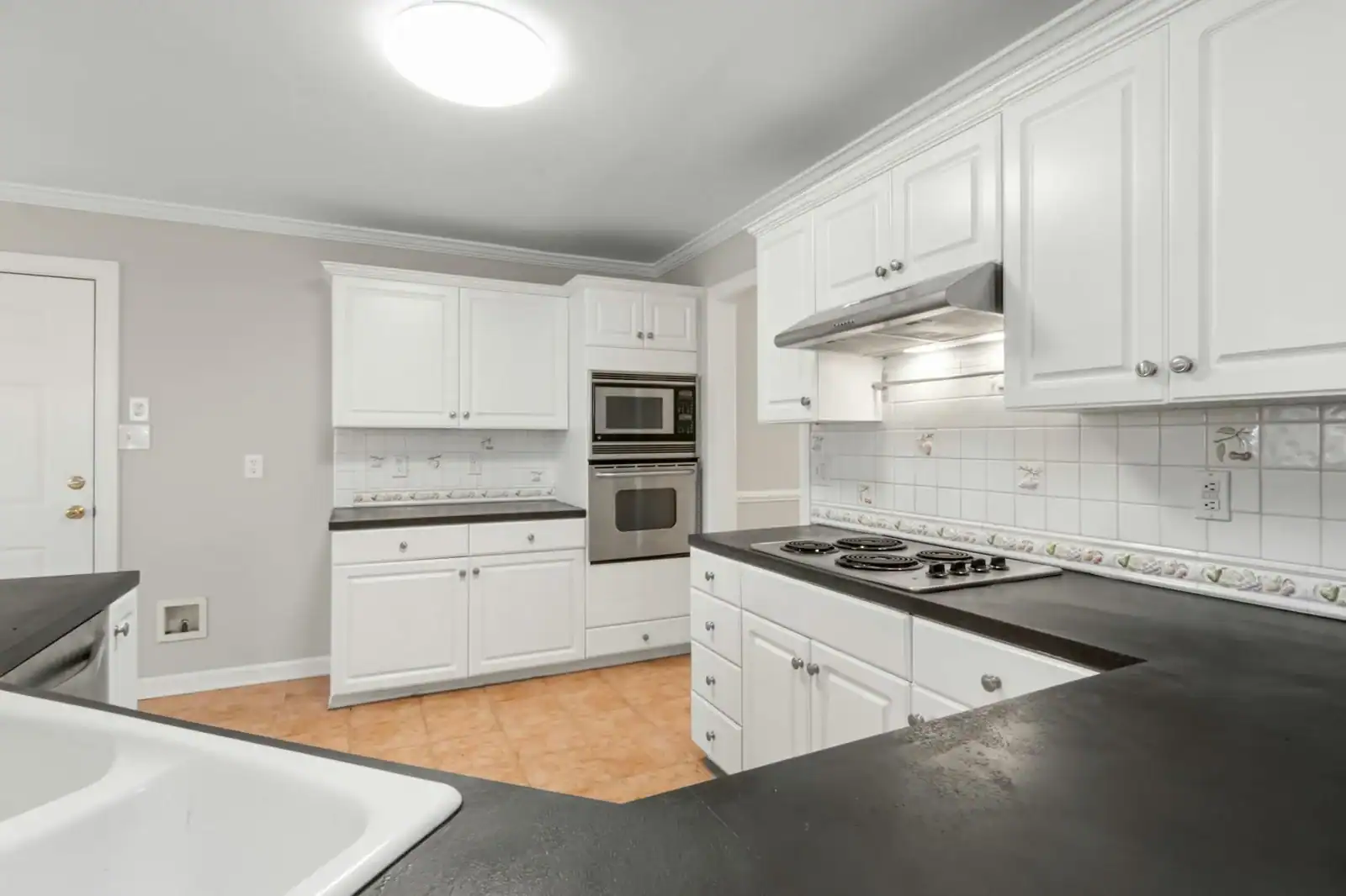 A clean and modern kitchen featuring white cabinets and black countertops with elegant lighting.