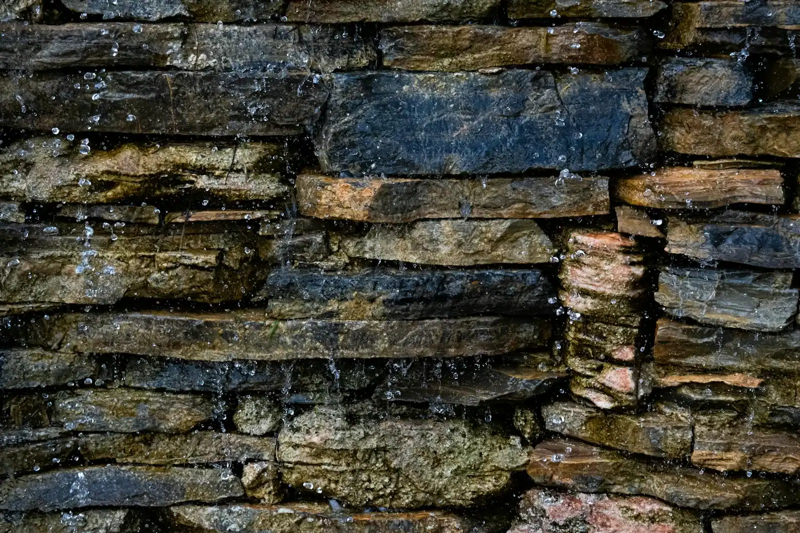 Close-up of water trickling over a natural stone wall in Istanbul.
