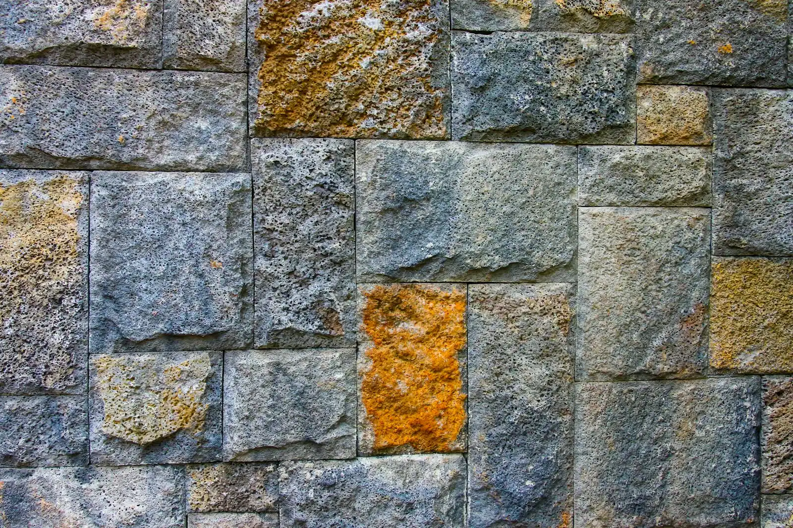 Detailed view of a textured stone wall showcasing varying colors and rough surfaces.