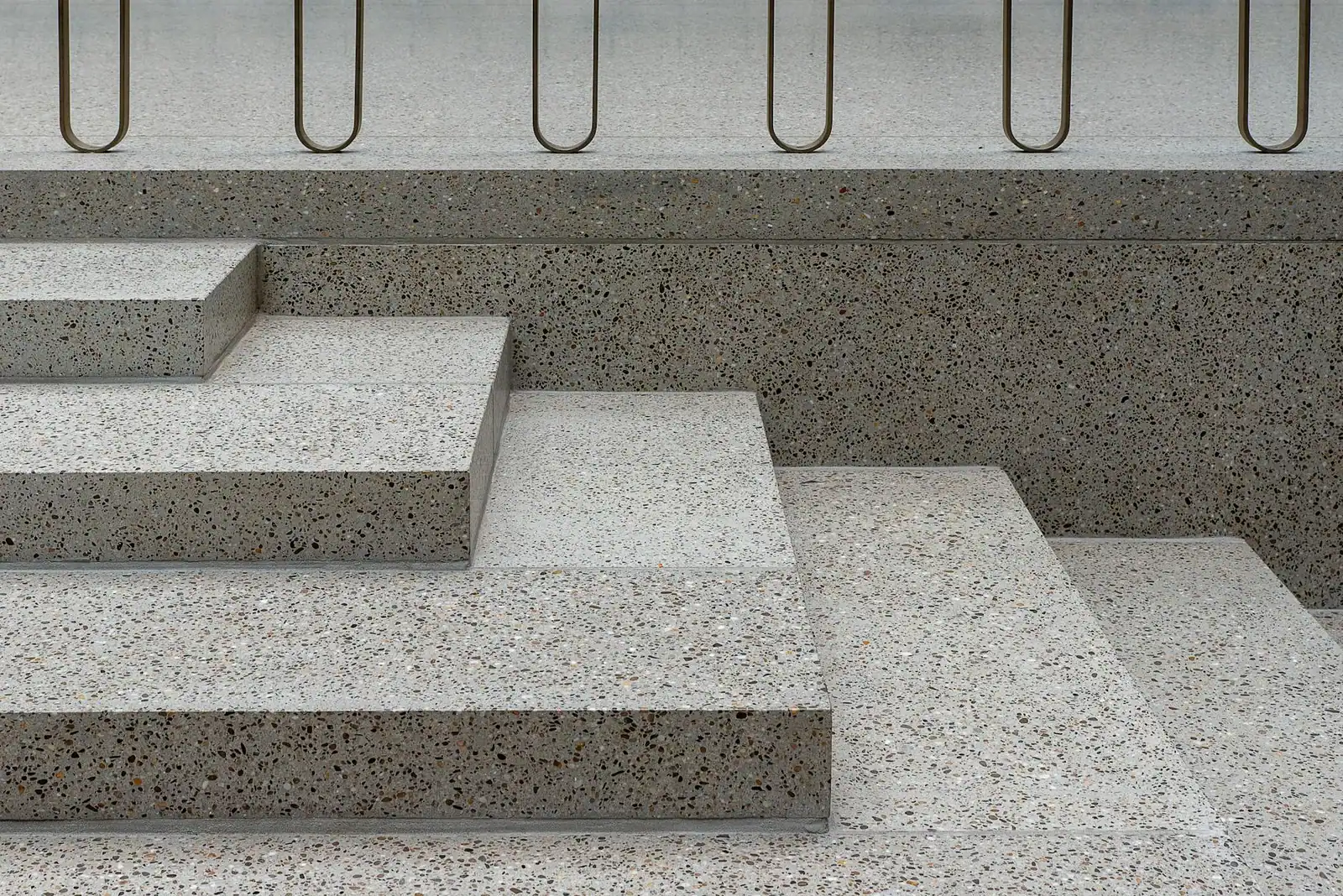 Minimalist concrete staircase featuring terrazzo texture and sleek metal railings.